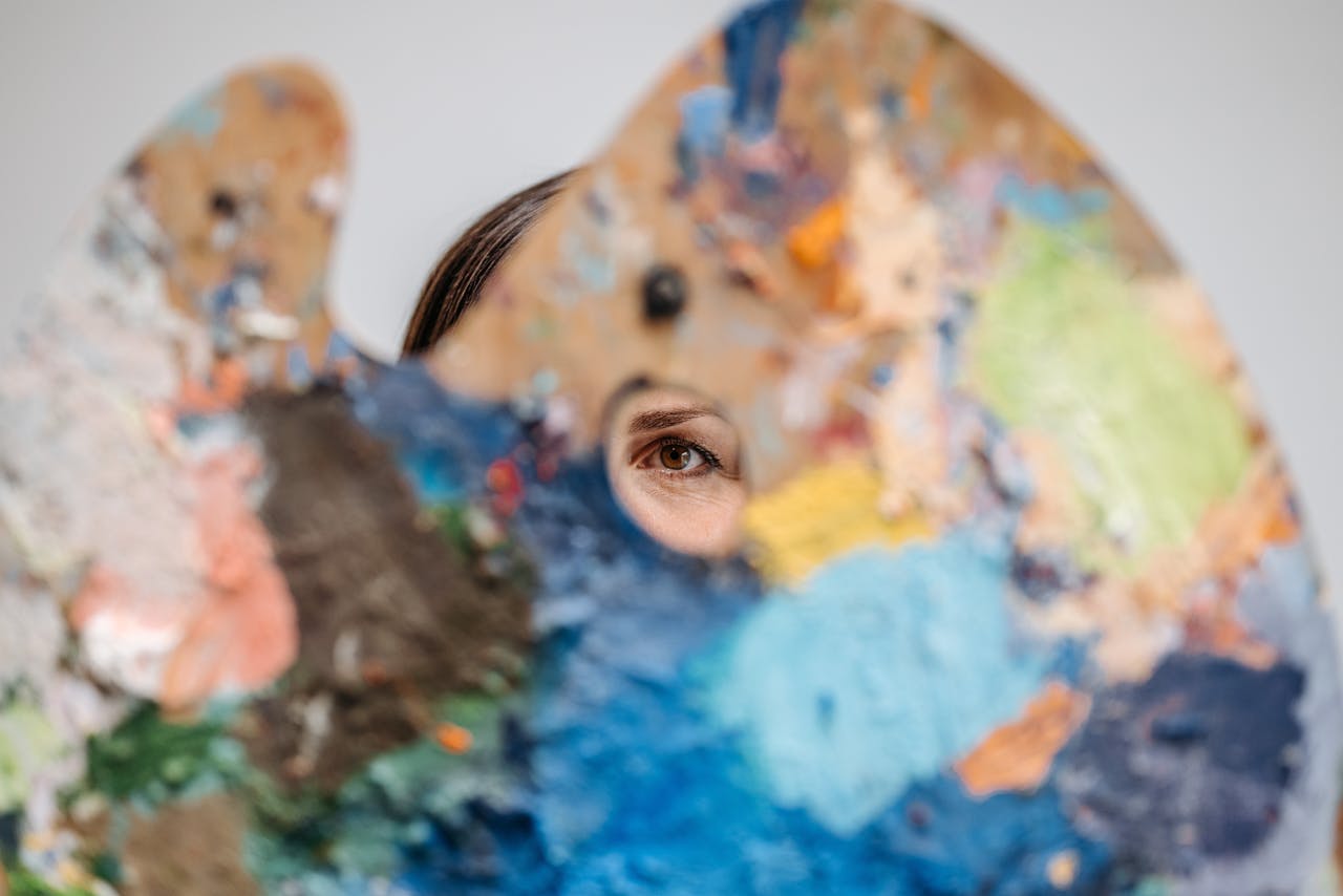An eye peers through a vibrant artists palette, symbolizing creativity and art exploration.